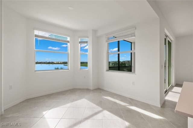 spare room featuring light tile patterned flooring and a water view