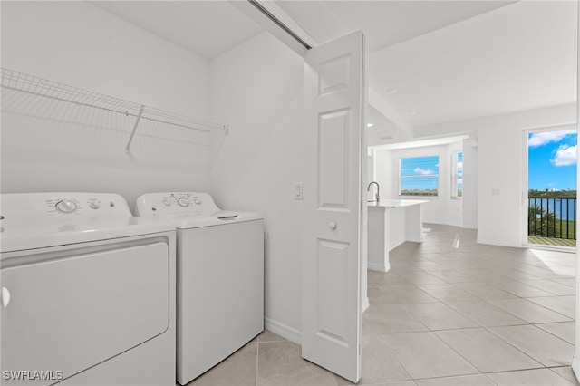 laundry area featuring a wealth of natural light, separate washer and dryer, and light tile patterned floors