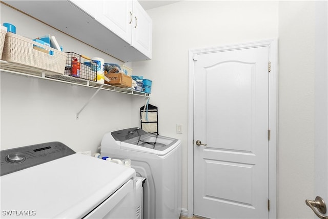 clothes washing area with cabinets and washer and dryer