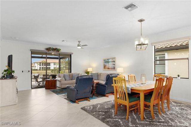 tiled dining area featuring crown molding and ceiling fan with notable chandelier