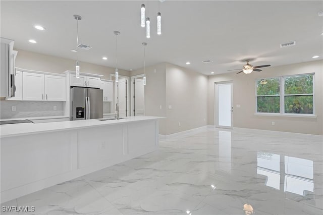 kitchen featuring decorative light fixtures, sink, white cabinets, backsplash, and stainless steel refrigerator with ice dispenser