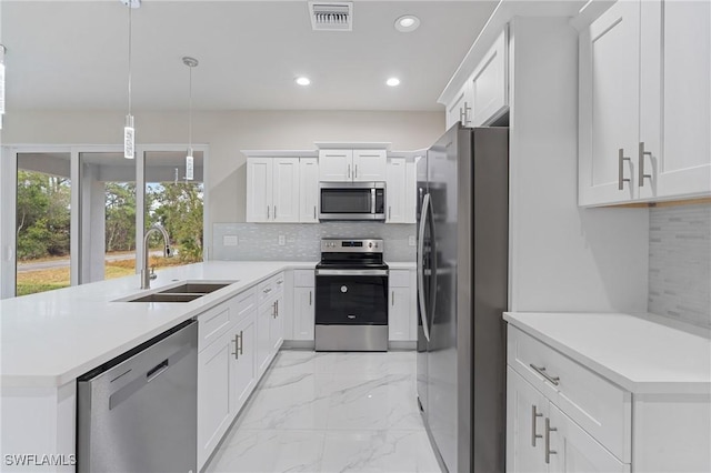 kitchen with sink, appliances with stainless steel finishes, white cabinetry, tasteful backsplash, and decorative light fixtures