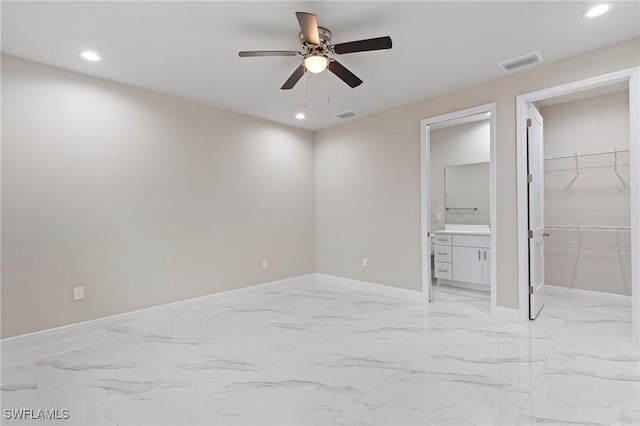 unfurnished bedroom featuring ceiling fan, a spacious closet, ensuite bath, and a closet