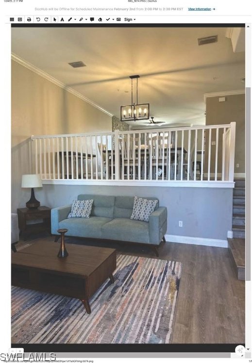 living room featuring hardwood / wood-style flooring, ornamental molding, and a notable chandelier