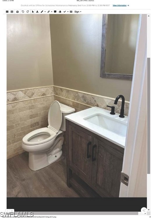 bathroom featuring hardwood / wood-style flooring, vanity, toilet, and tile walls