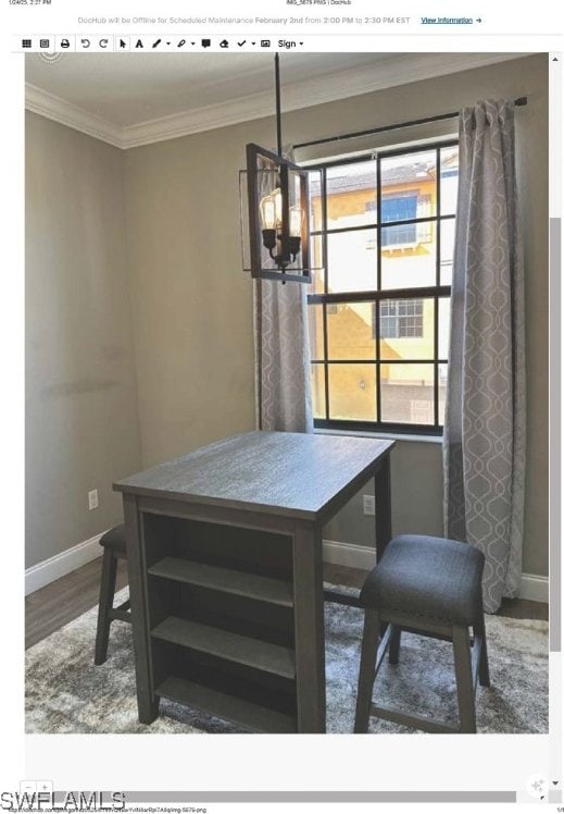 dining space with hardwood / wood-style flooring, ornamental molding, and an inviting chandelier