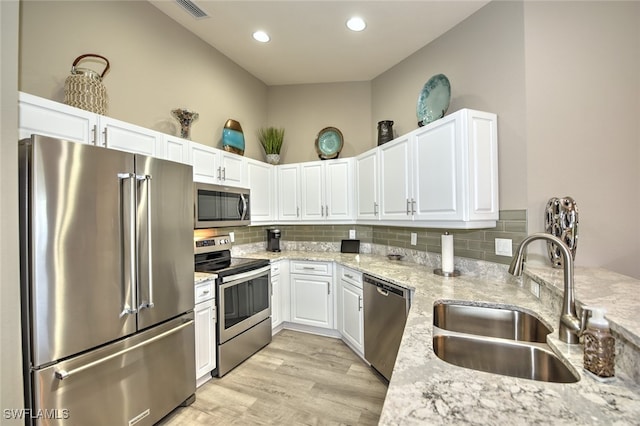 kitchen with light stone counters, sink, white cabinetry, and stainless steel appliances