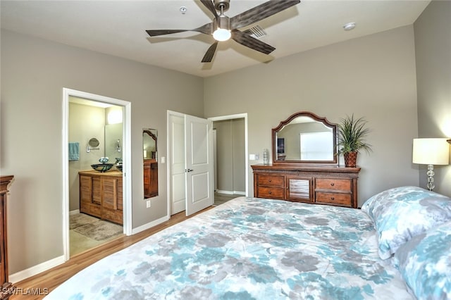 bedroom with connected bathroom, light hardwood / wood-style floors, and ceiling fan