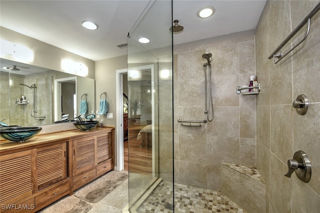 bathroom with tiled shower and vanity