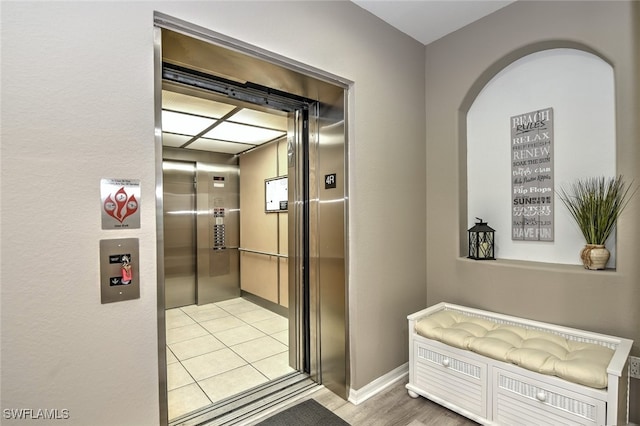 hall featuring elevator and light tile patterned floors