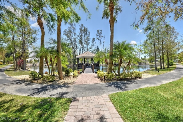 view of property's community with a gazebo, a water view, and a lawn