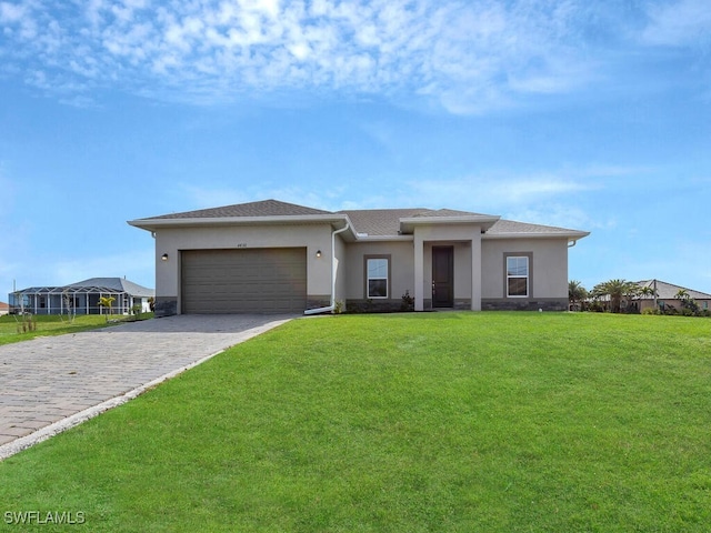 prairie-style home with a shingled roof, a front yard, stucco siding, decorative driveway, and a garage