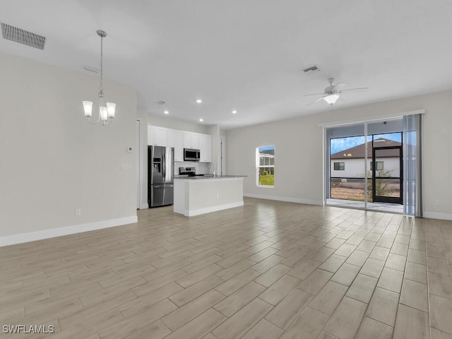 unfurnished living room with ceiling fan with notable chandelier