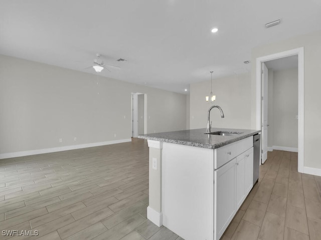 kitchen featuring sink, white cabinetry, decorative light fixtures, a center island with sink, and ceiling fan