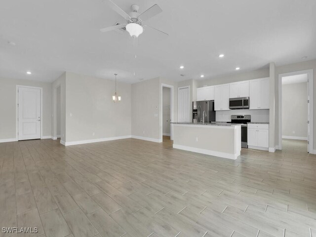 unfurnished living room with ceiling fan with notable chandelier