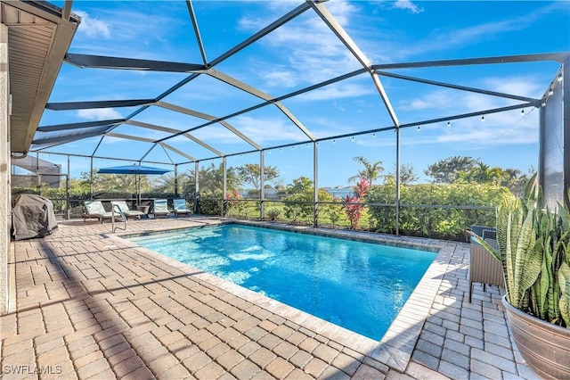 view of swimming pool with grilling area, a patio, and glass enclosure