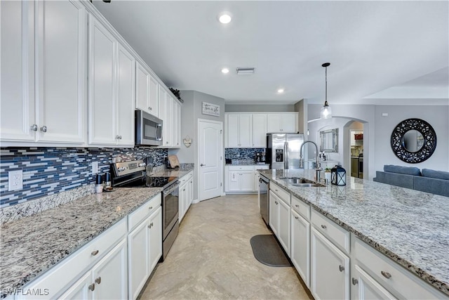 kitchen featuring sink, white cabinetry, hanging light fixtures, appliances with stainless steel finishes, and light stone countertops