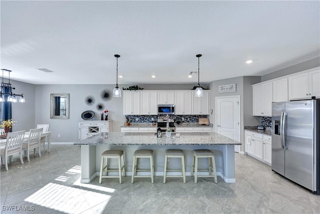 kitchen featuring appliances with stainless steel finishes, a breakfast bar, a kitchen island with sink, and white cabinets