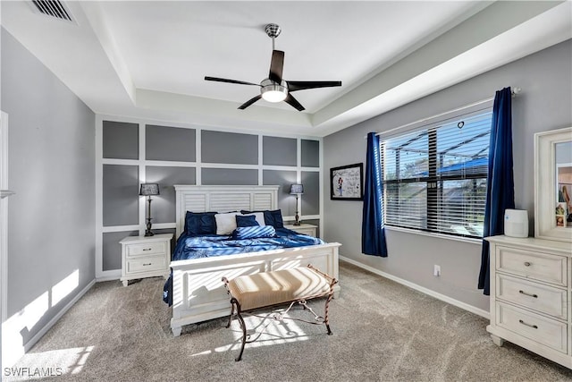 bedroom featuring light colored carpet, a raised ceiling, and ceiling fan