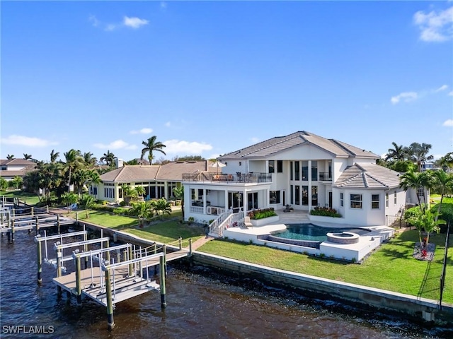 rear view of property featuring a yard, a water view, a patio area, a pool with hot tub, and a balcony