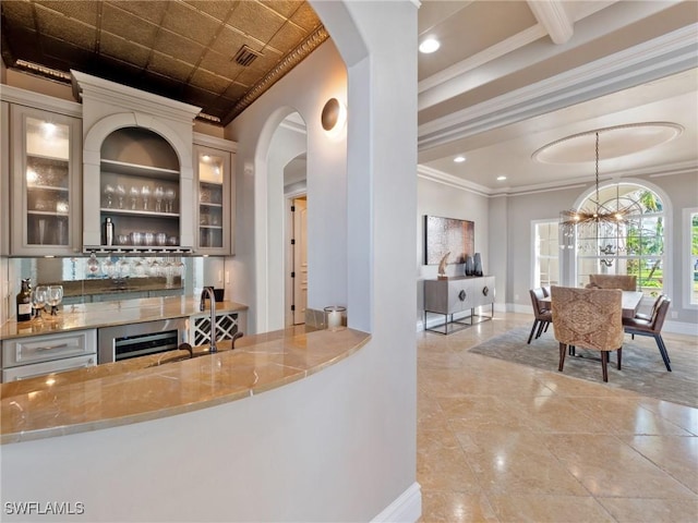 bar with pendant lighting, sink, light stone counters, a notable chandelier, and ornamental molding