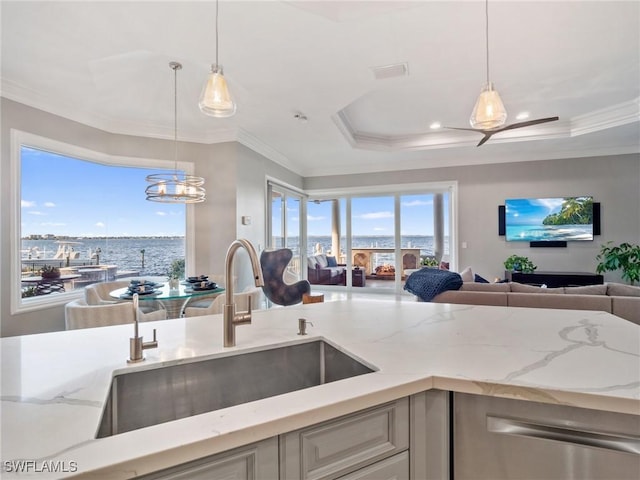 kitchen with decorative light fixtures, sink, ornamental molding, light stone counters, and a water view