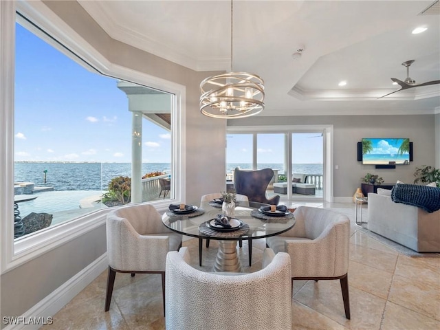 dining room featuring a raised ceiling, crown molding, a water view, and a notable chandelier