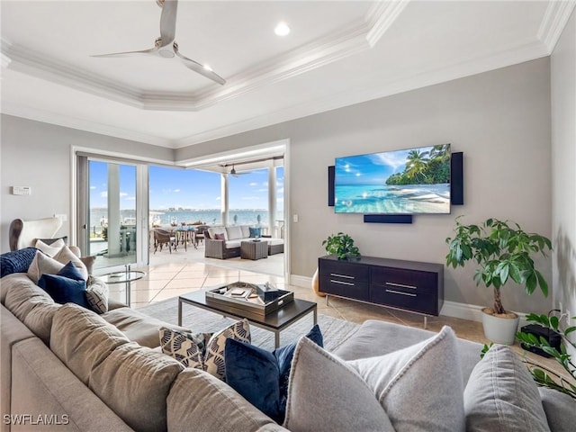 tiled living room featuring a raised ceiling, ornamental molding, and ceiling fan