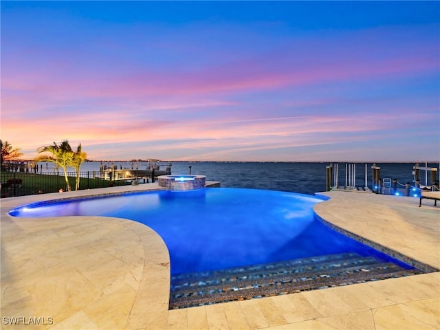 pool at dusk with a water view, an in ground hot tub, and a patio