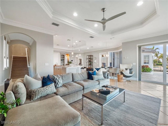 tiled living room featuring crown molding, ceiling fan, and a tray ceiling