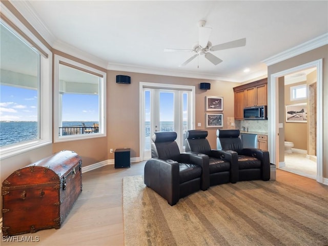 cinema room featuring ceiling fan, ornamental molding, and light wood-type flooring