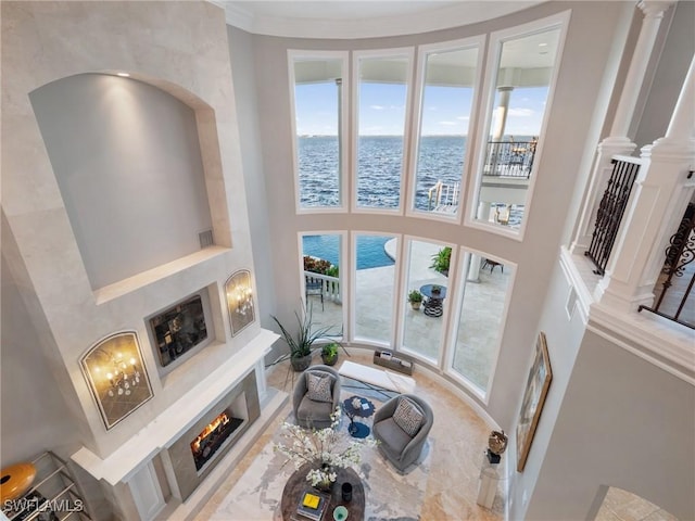 living room with ornate columns, a water view, a high ceiling, and a wealth of natural light