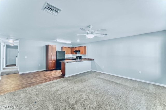 kitchen with sink, black fridge, carpet flooring, kitchen peninsula, and ceiling fan