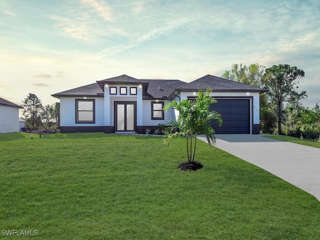 prairie-style house featuring a garage and a yard