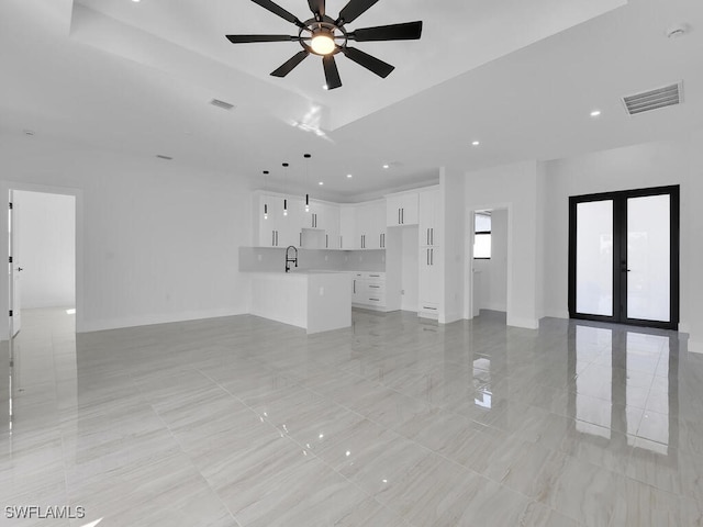 unfurnished living room featuring sink, french doors, and ceiling fan