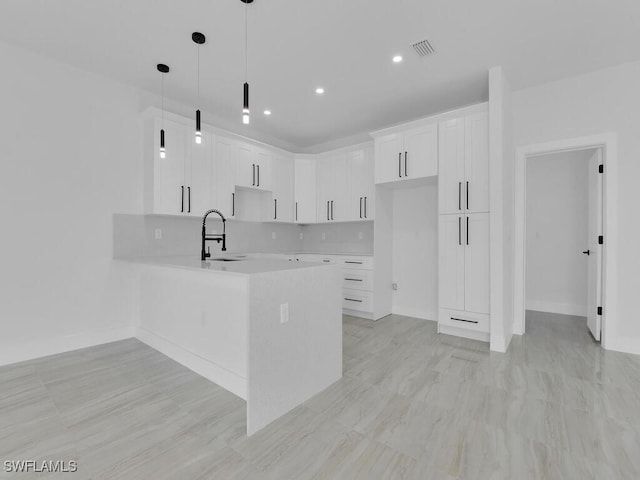 kitchen with pendant lighting, sink, white cabinetry, tasteful backsplash, and kitchen peninsula