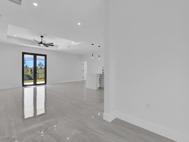 empty room featuring a raised ceiling, sink, and ceiling fan