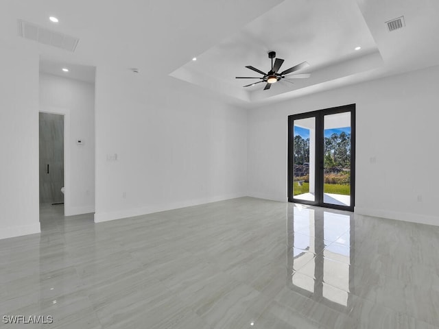 empty room with ceiling fan and a tray ceiling