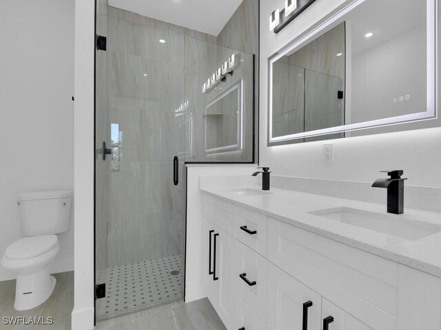 bathroom with vanity, a shower with shower door, and toilet