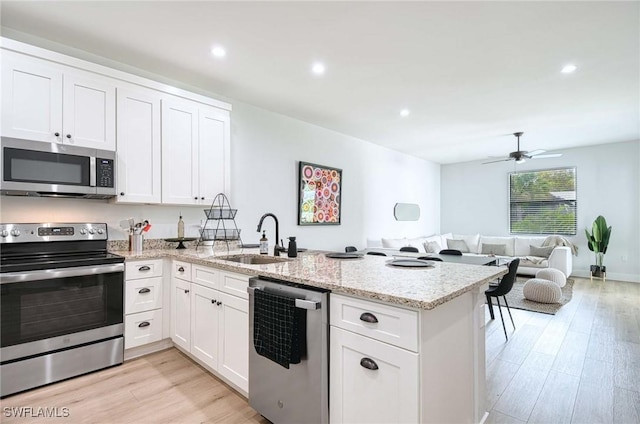 kitchen featuring white cabinetry, sink, light stone counters, and appliances with stainless steel finishes