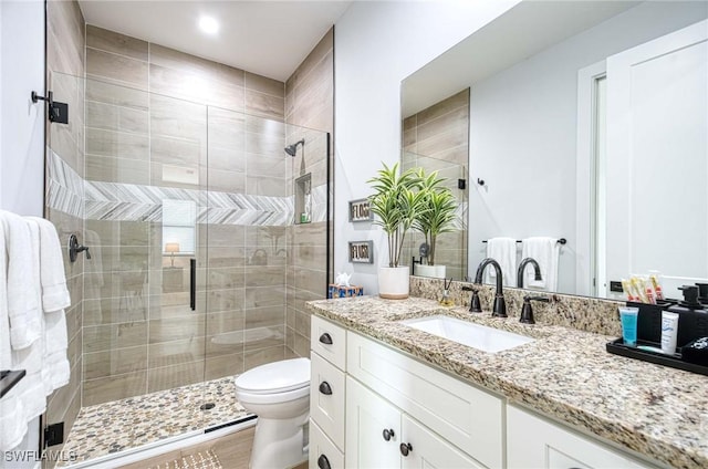 bathroom featuring hardwood / wood-style flooring, vanity, a shower with shower door, and toilet