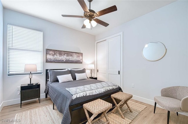 bedroom featuring light hardwood / wood-style floors, ceiling fan, and a closet