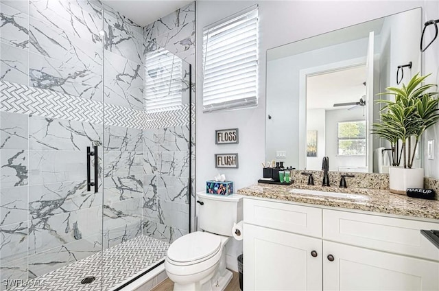 bathroom with walk in shower, ceiling fan, vanity, and toilet