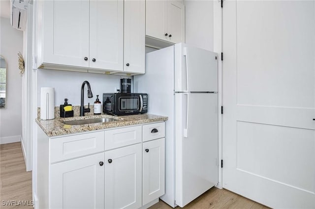 kitchen with white fridge, sink, and white cabinets