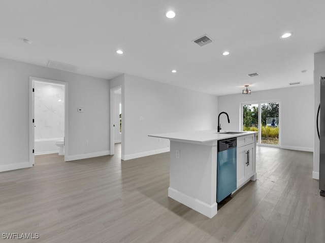 kitchen with sink, white cabinetry, light hardwood / wood-style flooring, stainless steel dishwasher, and an island with sink