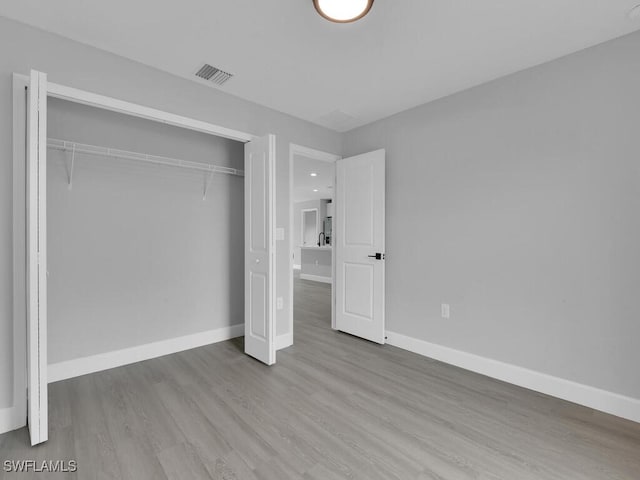 unfurnished bedroom featuring light hardwood / wood-style flooring and a closet