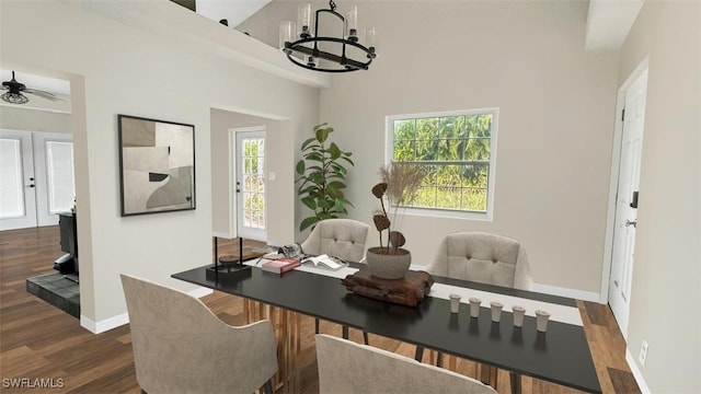 dining space with ceiling fan with notable chandelier, plenty of natural light, and dark hardwood / wood-style floors