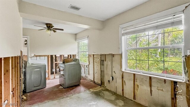 clothes washing area featuring washer / dryer, a wood stove, and ceiling fan