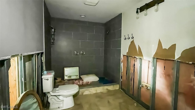 bathroom with a tile shower and toilet