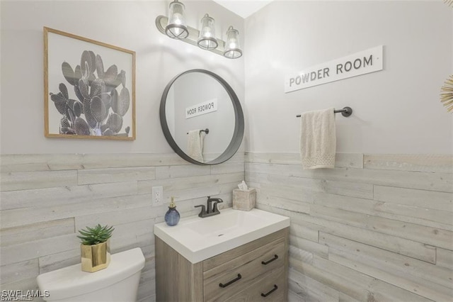 bathroom featuring vanity, tile walls, and toilet